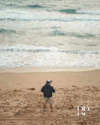 a man standing on the beach looking at the ocean